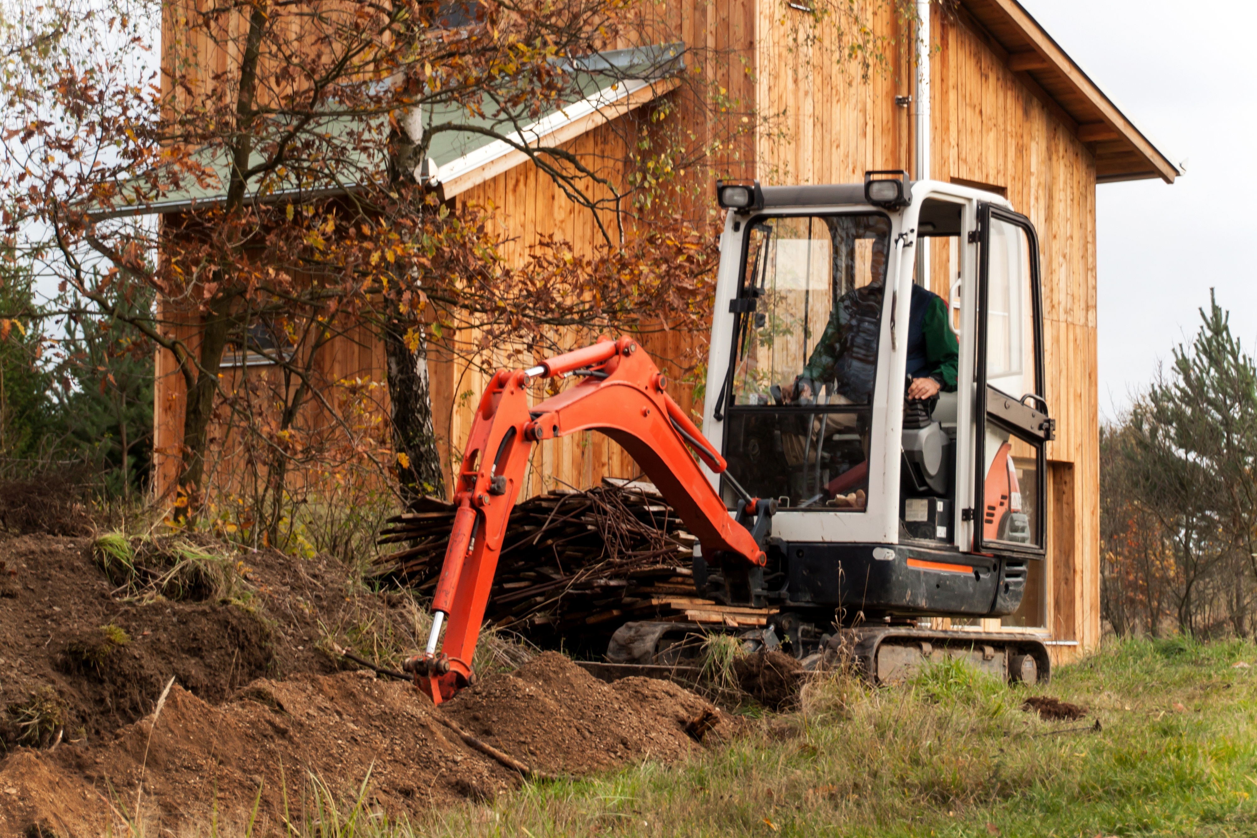 Mini excavator on construction site. Construction of a family house near a forest.